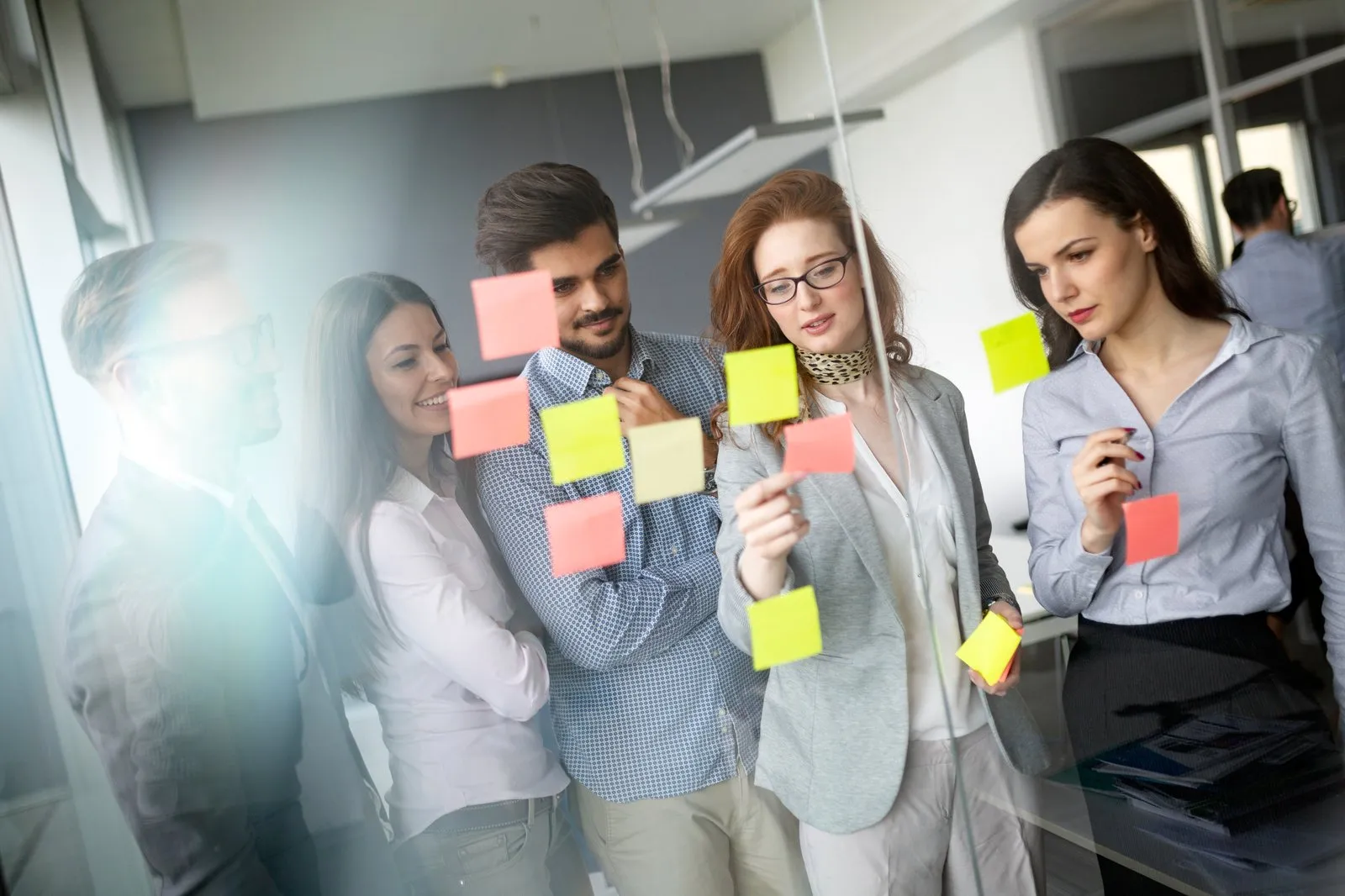 Team plant ein Projekt mit Haftnotizen an einer Glaswand