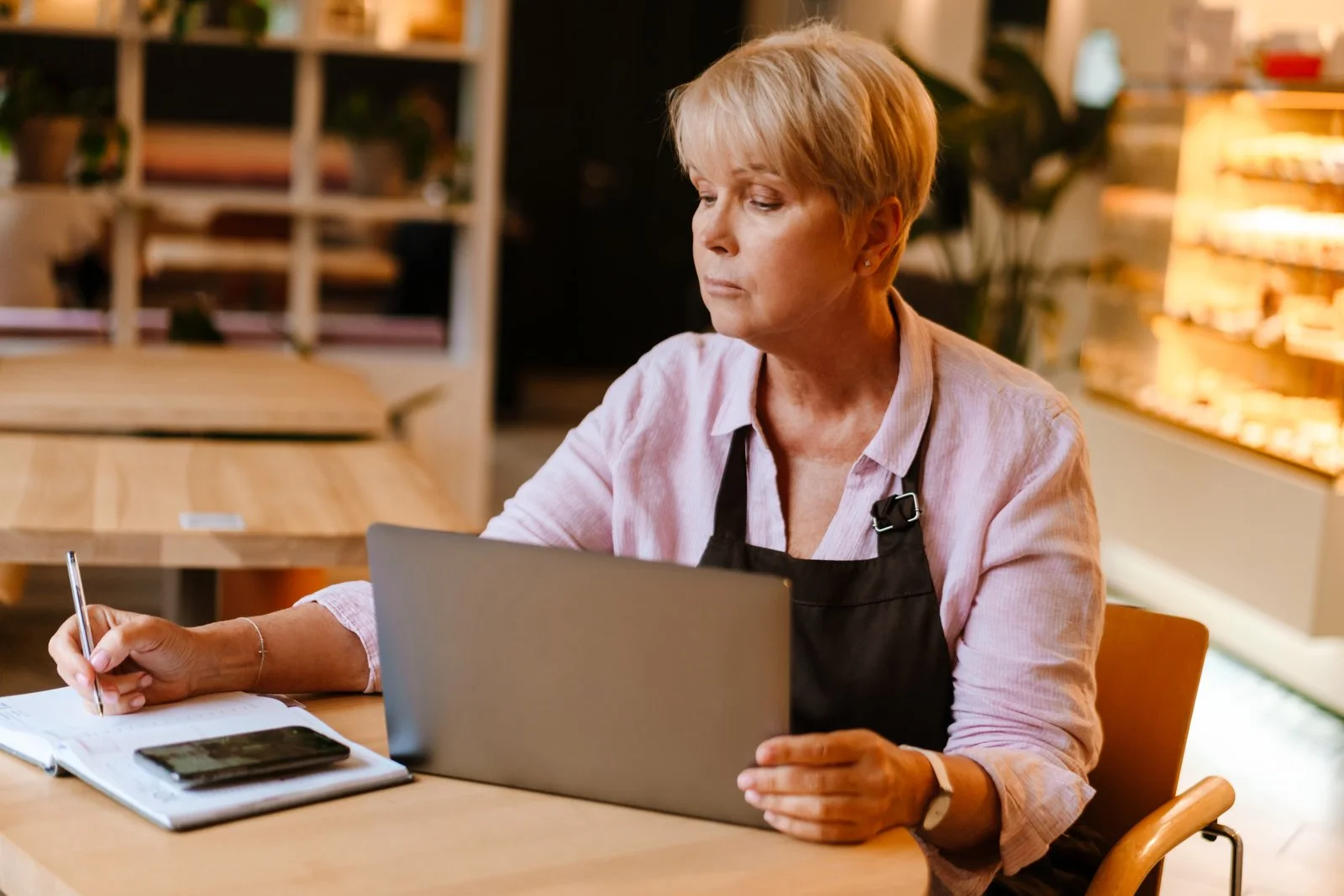 Frau arbeitet in einem Café am Laptop und macht Notizen